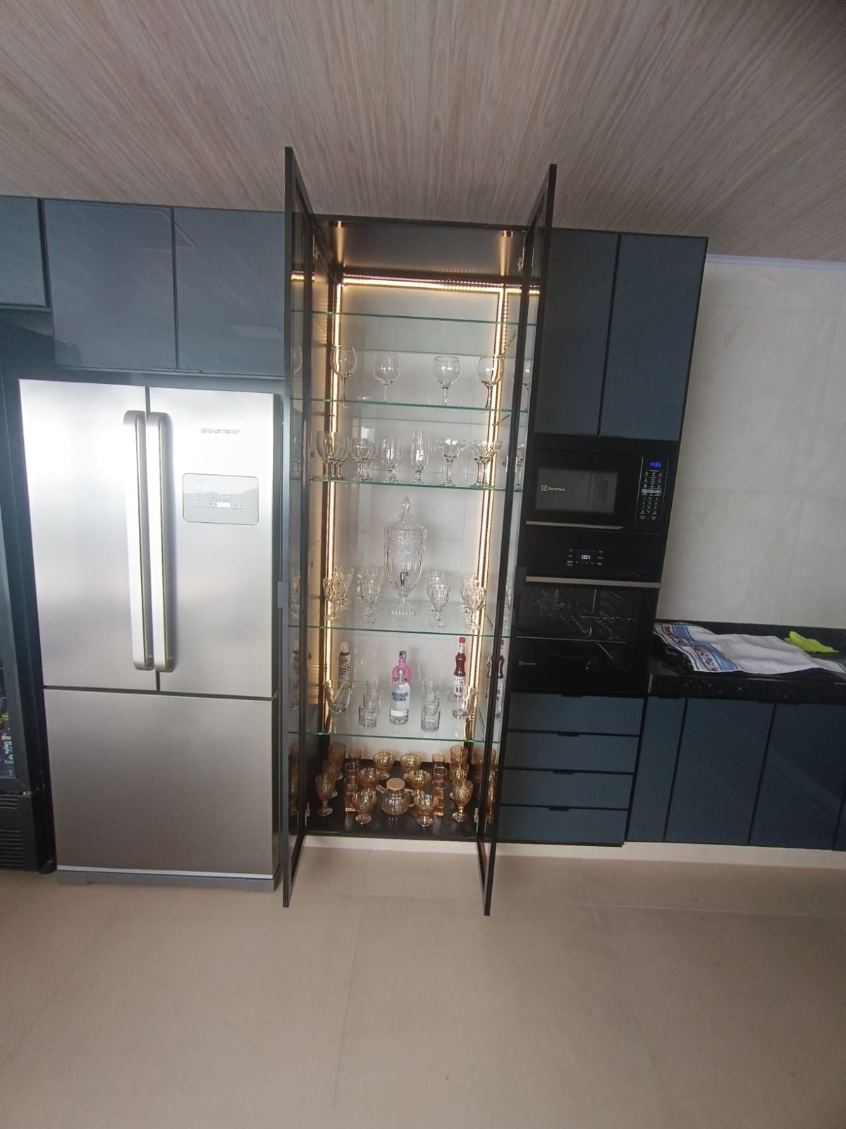 Cozinha gourmet com cristaleira iluminada em vidro e alumínio